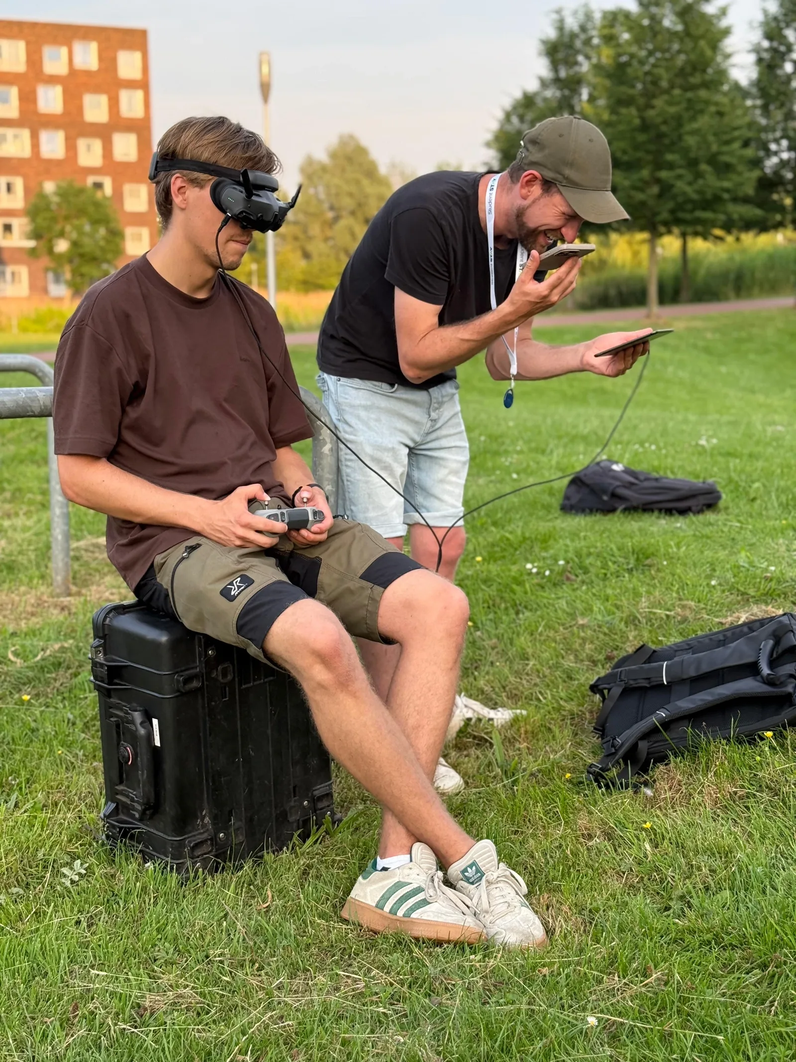 FPV-piloot met goggles, terwijl figuranten via de telefoon hun seintje krijgen