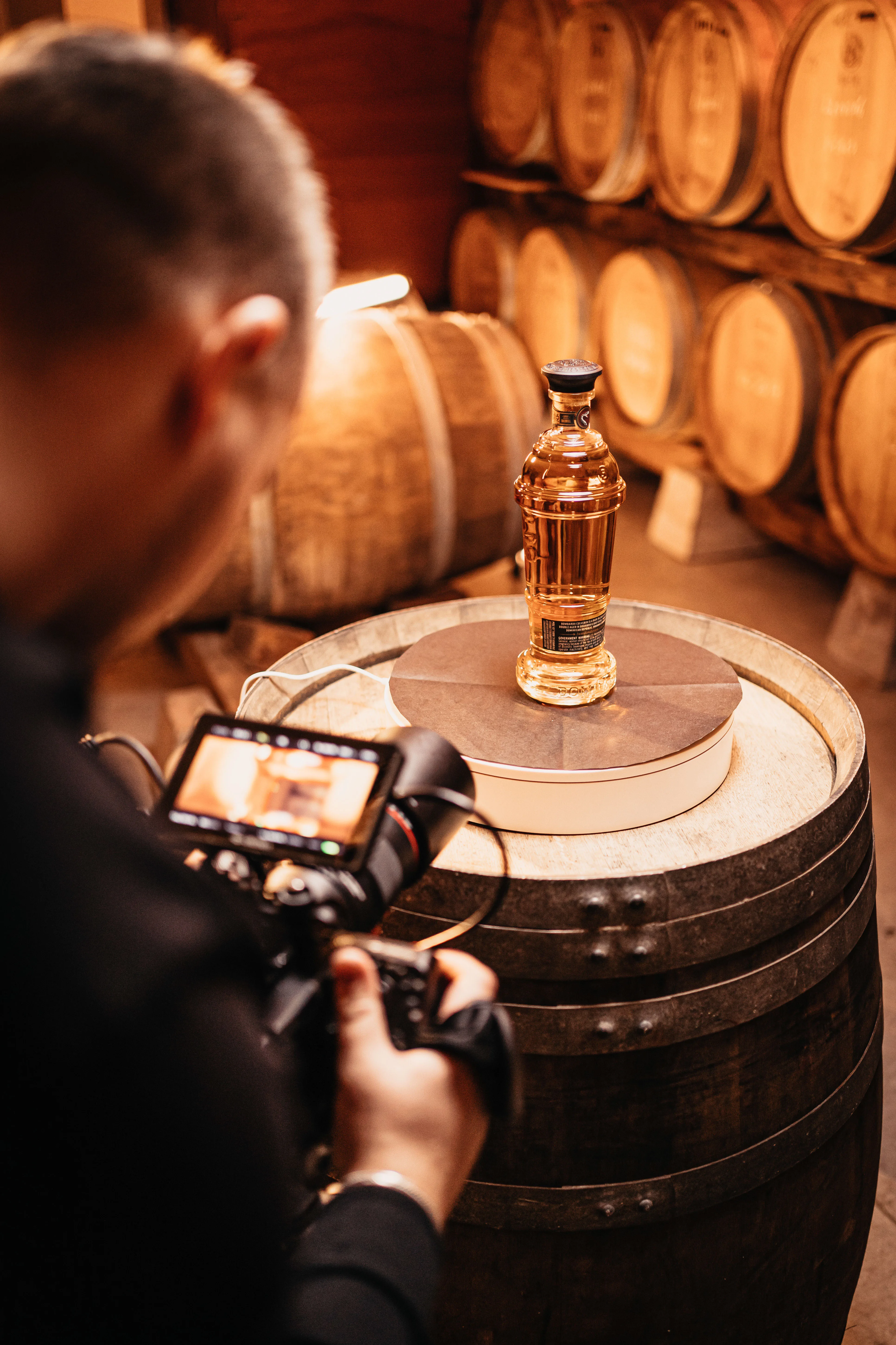 Studio shoot bij Weduwe Joustra · Bombarda fles op een rumvat, cameraman erachter