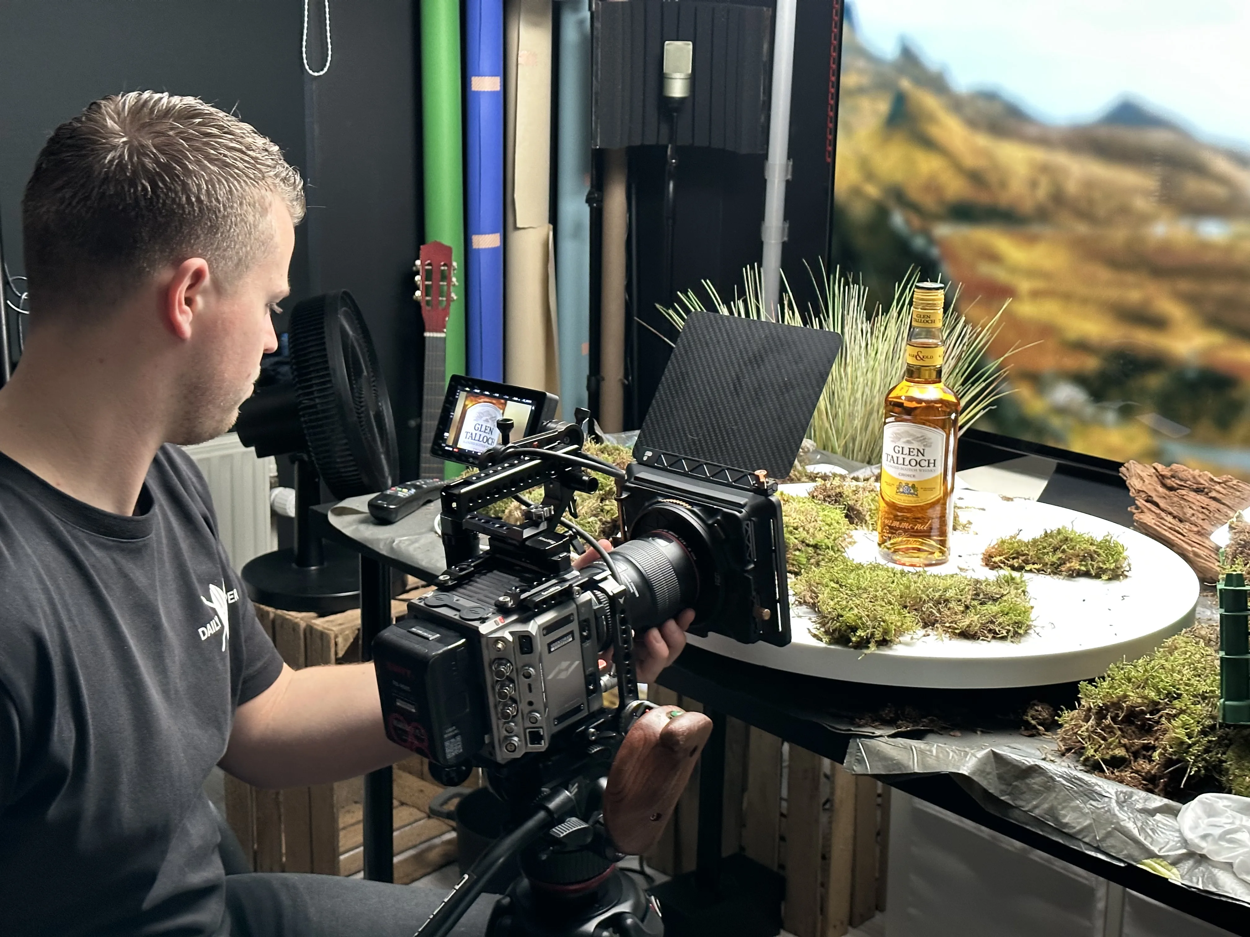 Chris filmt de fles op het draaiplateau, voor de OLED met Schots landschap