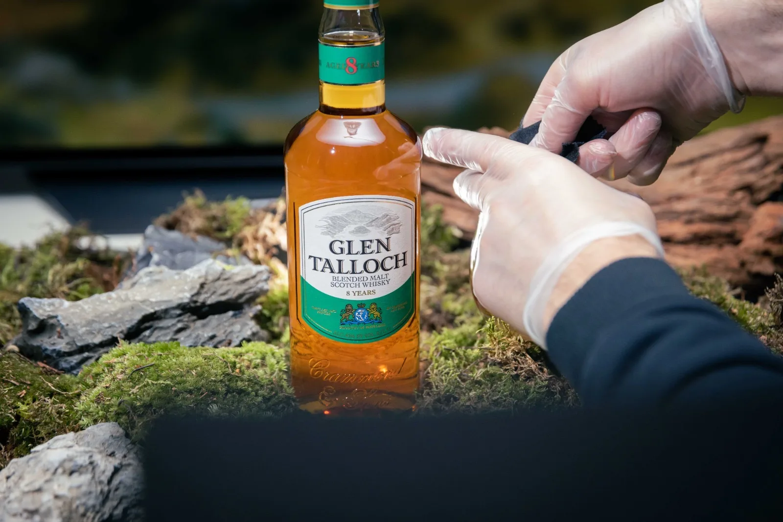Handen met latex handschoenen plaatsen de Glen Talloch fles op het mos. We dragen ze tegen vingerafdrukken: de macrolens ziet alles, ook iets wat je met het oog niet ziet.