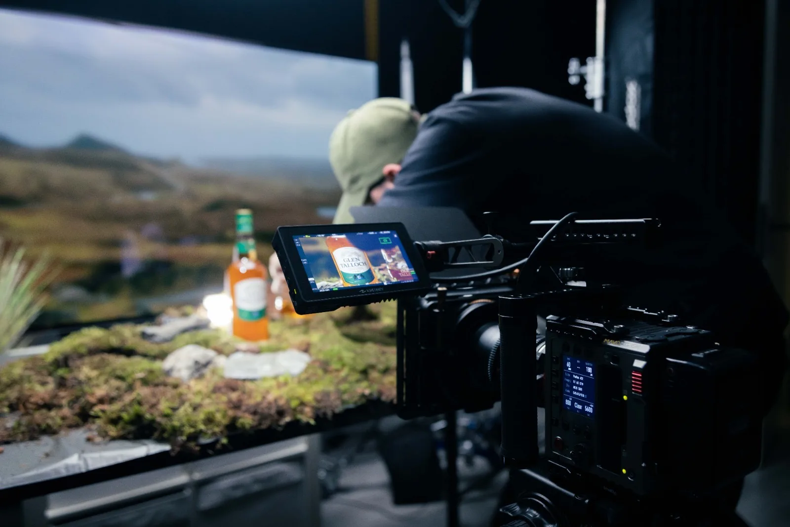 Cinema-camera met monitor toont de fles tegen de Schotse highlands op de OLED, terwijl de fles op de mos-set staat